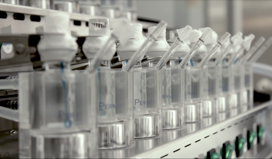 A line of plastic bottles on a topical drug product formulation machine.