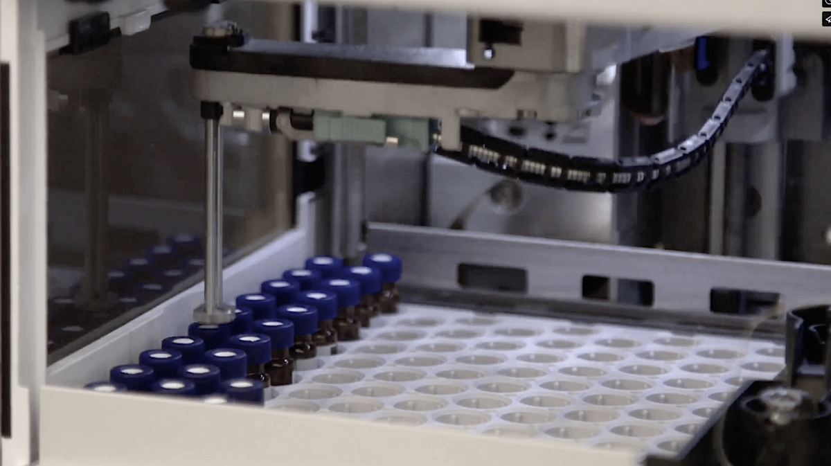 A machine for manufacturing topical drug products, with a lot of bottles in it.