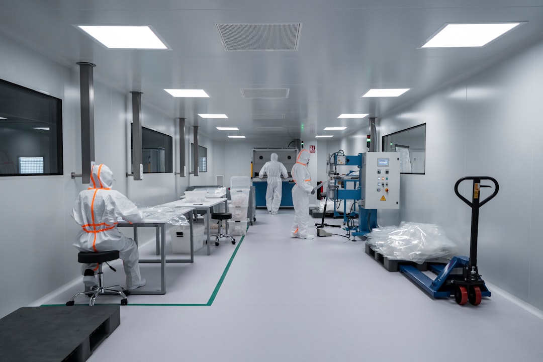 People in full protective suits work in a cleanroom laboratory with various equipment, tables, and machinery dedicated to GMP clinical manufacturing.
