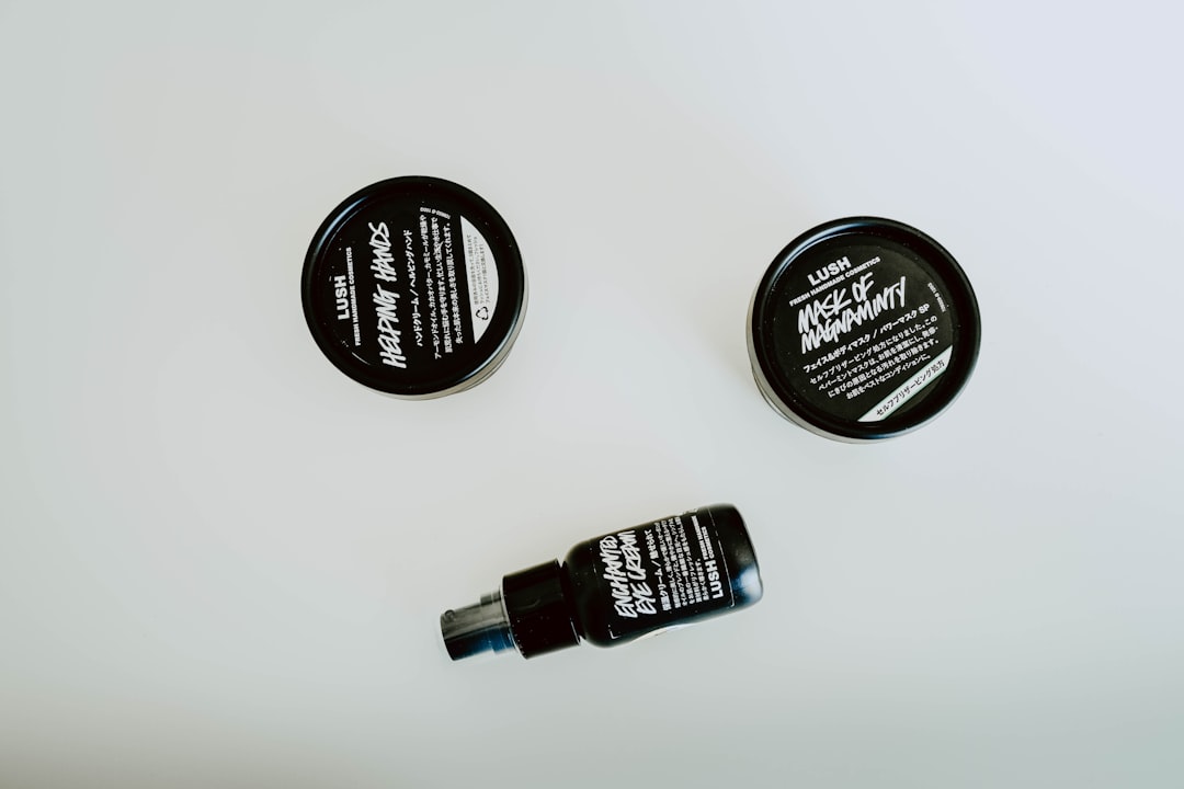 Three Lush cosmetic products—two round containers labeled "Helping Hands" and "Mask of Magnaminty," and a black spray bottle labeled "Eau Roma Water"—are displayed on a white background, reminiscent of innovative topical drug formulation.